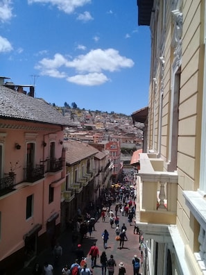A bustling urban street with buildings on either side, a clear sky, and people walking. - Hostal Quito Cultural (Quito)