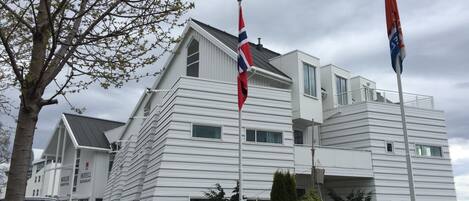 A modern hotel with a flat roof, multiple windows, and a flagpole with flags.