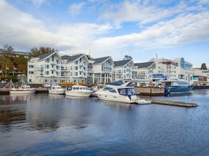 A marina with several boats docked, a modern building with multiple balconies, and a clear sky. - Molde Fjordhotell - by Classic Norway Hotels (Molde)