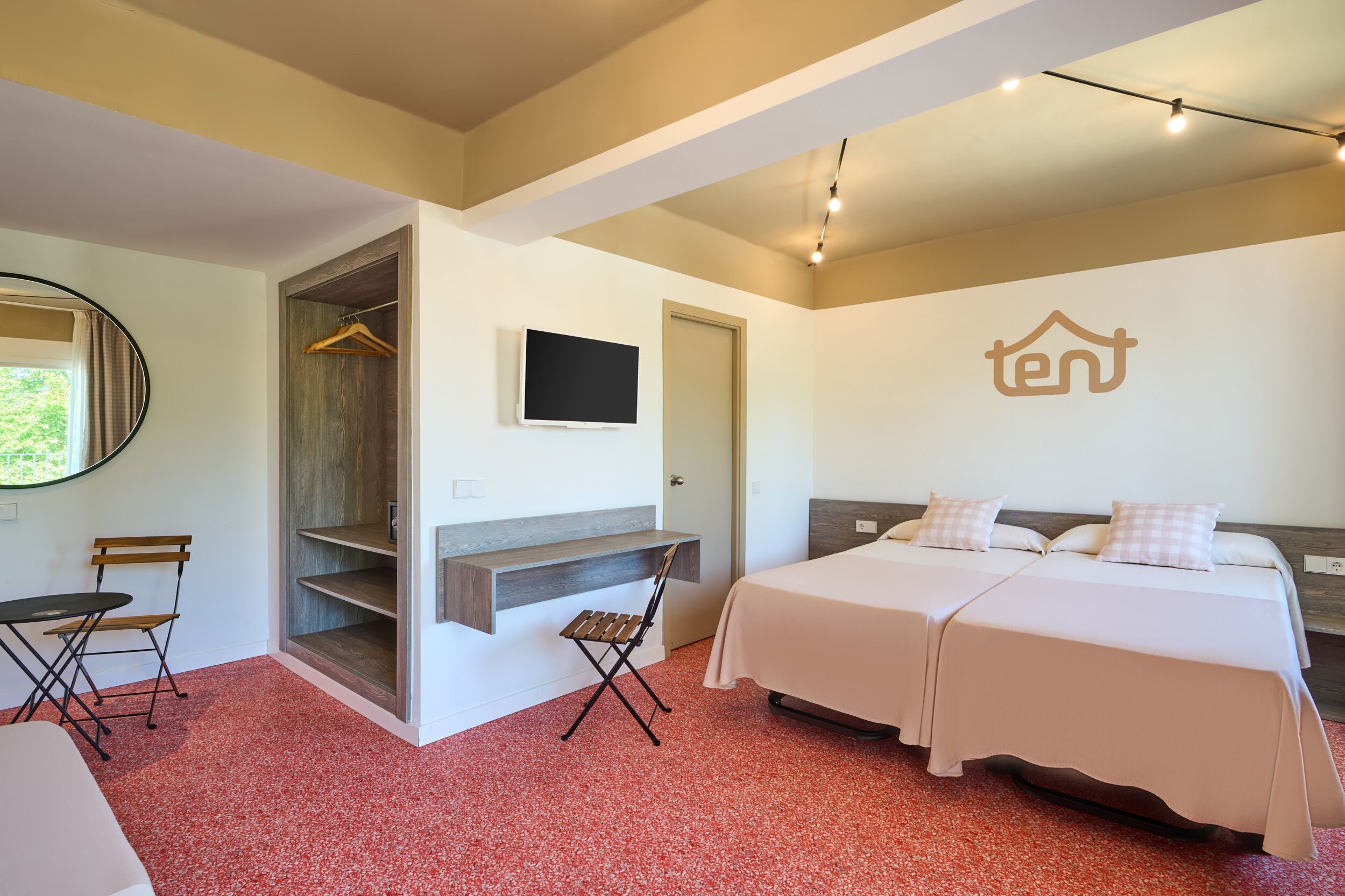 Un dormitorio con dos camas, televisión, armario, escritorio y una silla.