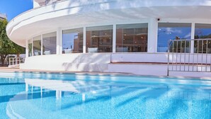 Un edificio moderno con piscina, ventanas amplias y un balcón.