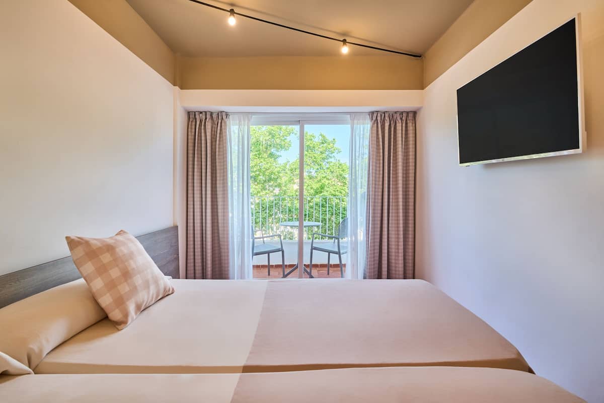 A hotel room with a large bed, a flat-screen TV, and a balcony with a table and chairs.
