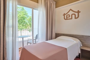 Una habitación de hotel con una cama, una mesita y un balcón con una silla.