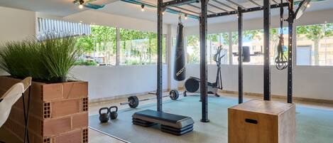 A gym with a pull-up bar, kettlebells, a punching bag, and a brick planter.