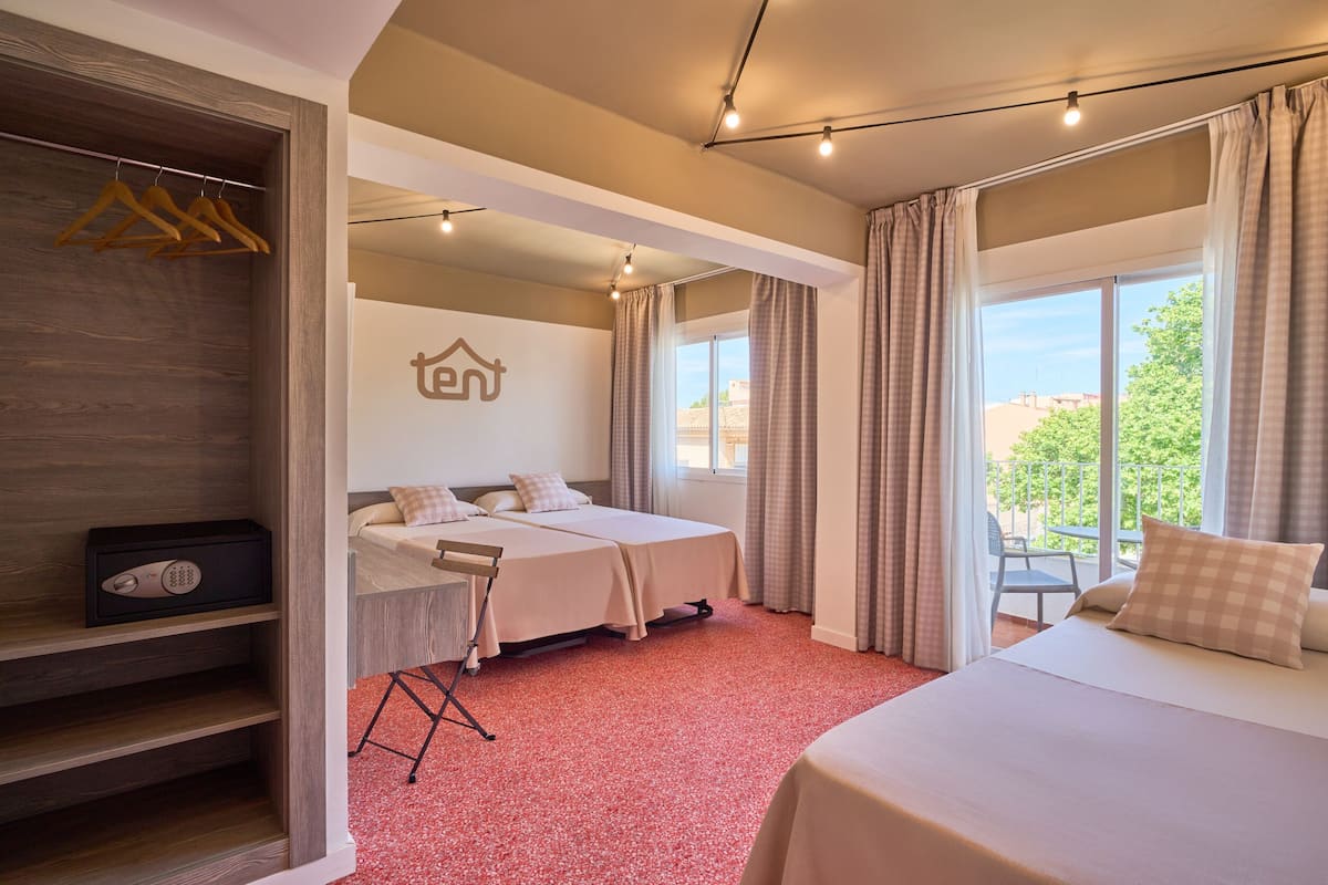 A hotel room with a bed, a desk, a wardrobe, and a window with curtains.