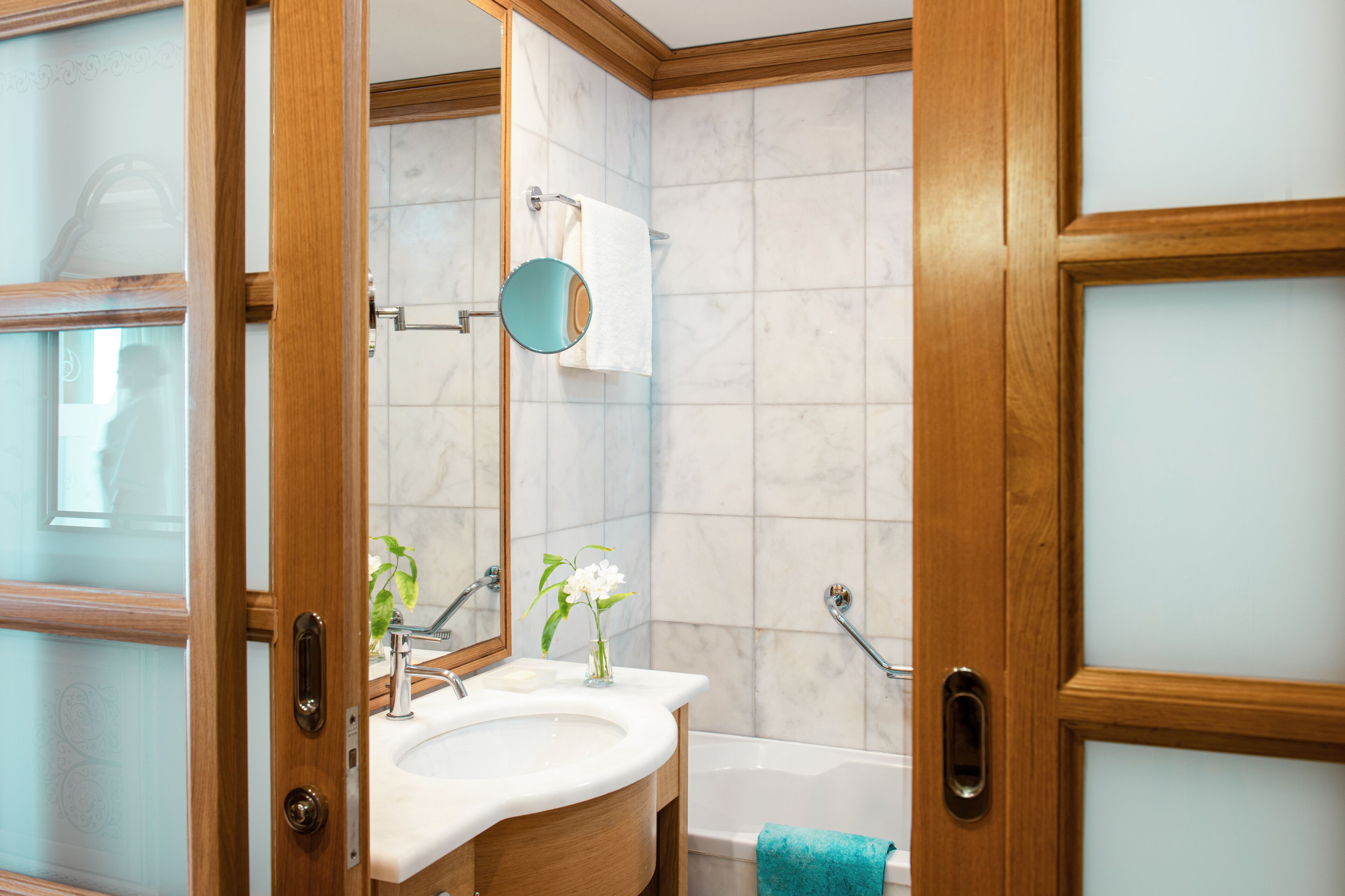 Un baño con tocador de madera, un lavamanos, un espejo, un perchero para toallas y una bañera.