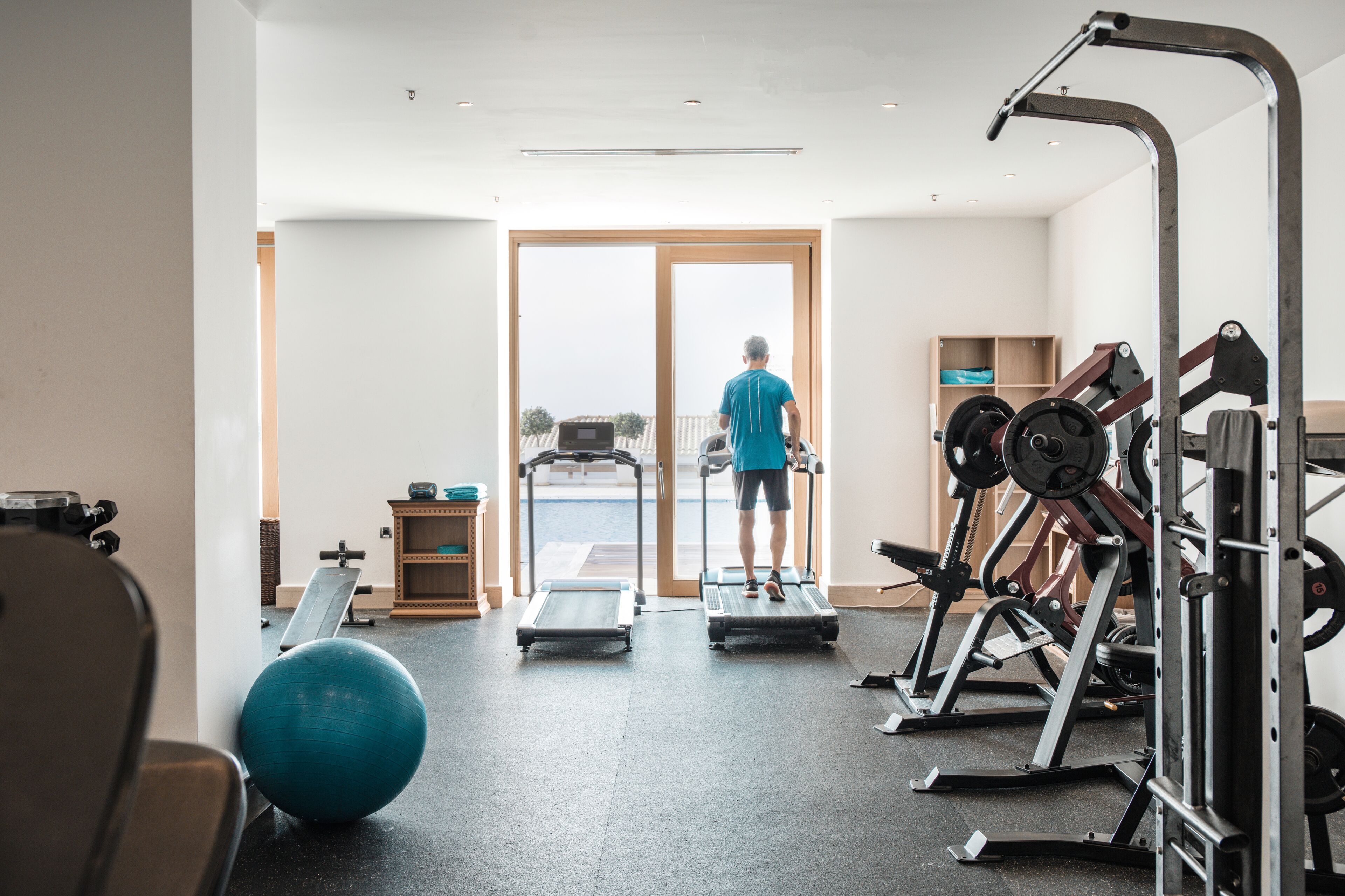 A gym with treadmills, a rowing machine, and weightlifting equipment.