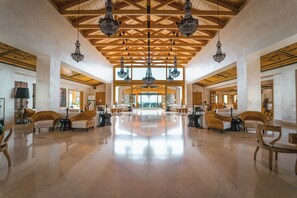 A spacious lobby with a high wooden ceiling, chandeliers, and a central seating area with sofas and chairs. - Mitsis Selection Blue Domes (Kos)