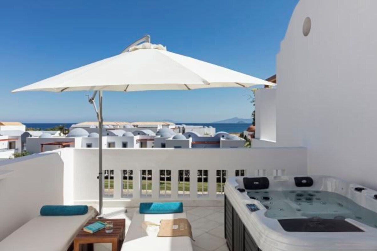 A rooftop terrace with a hot tub, lounge area, and umbrella.
