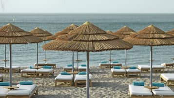 En la playa, arena negra, sillas reclinables de playa, sombrillas