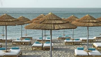 On the beach, black sand, sun-loungers, beach umbrellas