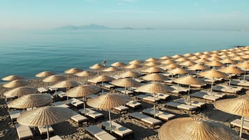On the beach, black sand, sun loungers, beach umbrellas