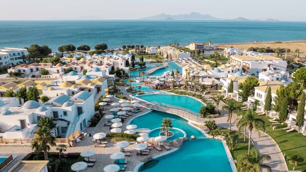 Un resort con varias piscinas, tumbonas y sombrillas.