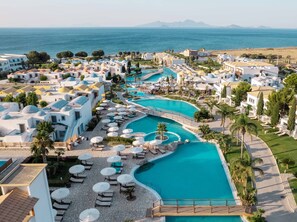 Un complex turístic amb diverses piscines, gandules i ombrelles.