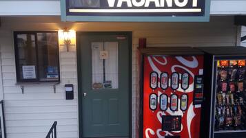 A building with a sign reading 'OFFICE VACANCY' and a Coca-Cola vending machine.