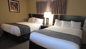 Two single beds with headboards, a nightstand with a lamp, and a framed picture on the wall. - Monroe Motel Near Seattle Everett WA (Monroe)