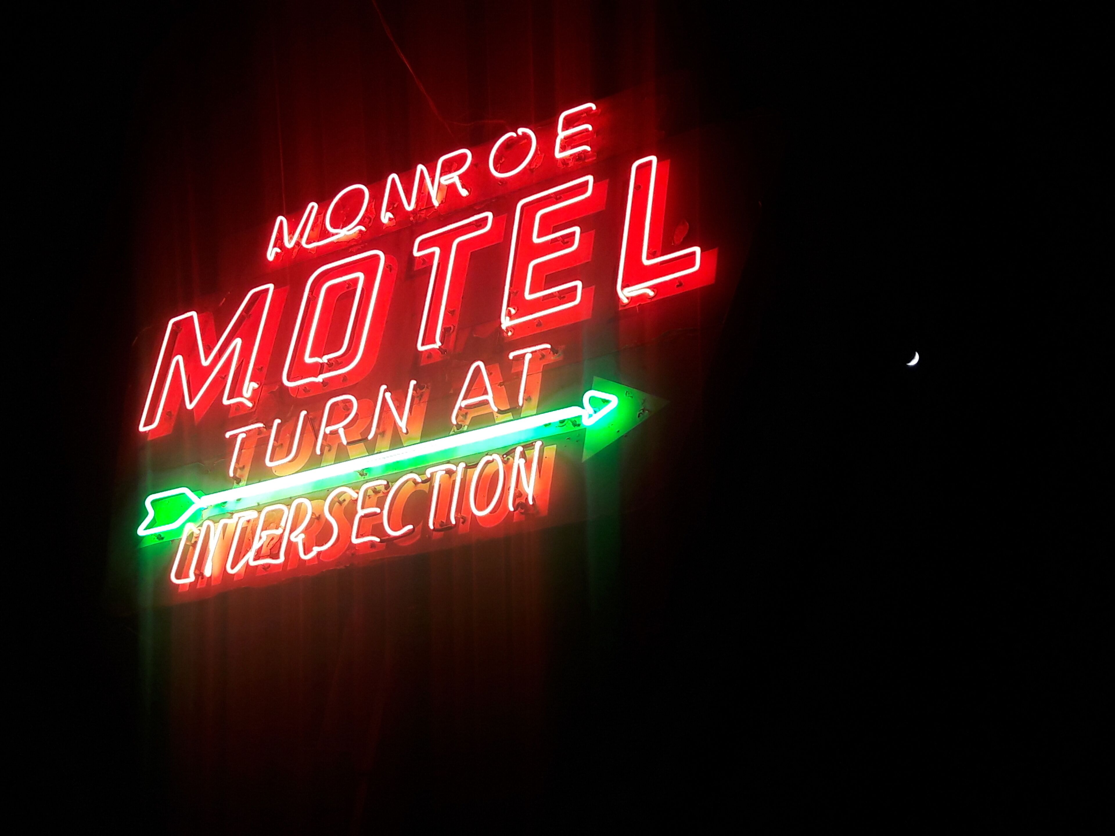 Une enseigne au néon pour le motel Monroe, avec l’inscription « TOURNER À L’INTERSECTION ».