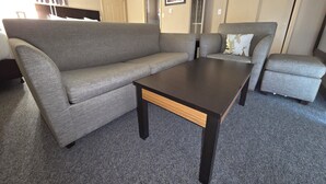 A living room with a grey sofa, a matching armchair, and a dark wooden coffee table. - Monroe Motel Near Seattle Everett WA (Monroe)