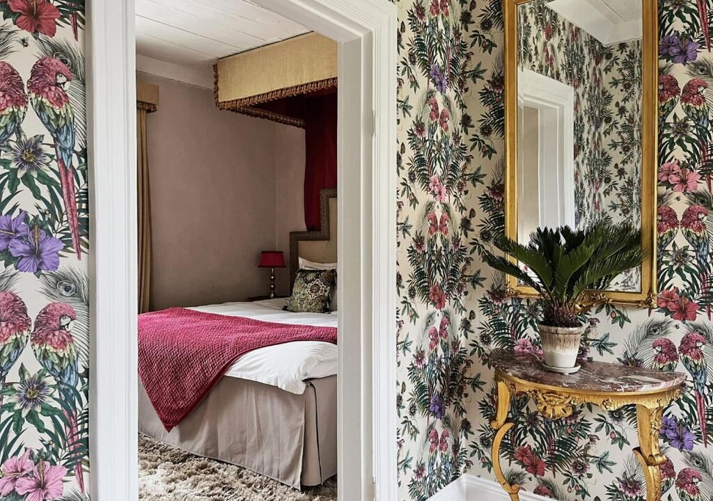Un dormitorio con cama, una mesita de noche con una planta y un espejo.