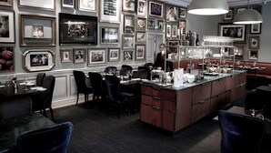 A restaurant with a bar area, framed pictures on the walls, and black upholstered chairs. - Görvälns Slott (Jarfalla)