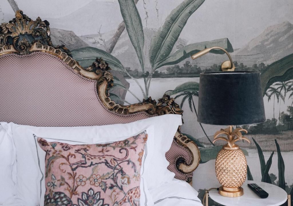 Un lit doté d’une tête de lit décorative, d’une lampe d’appoint et d’un coussin à motifs.