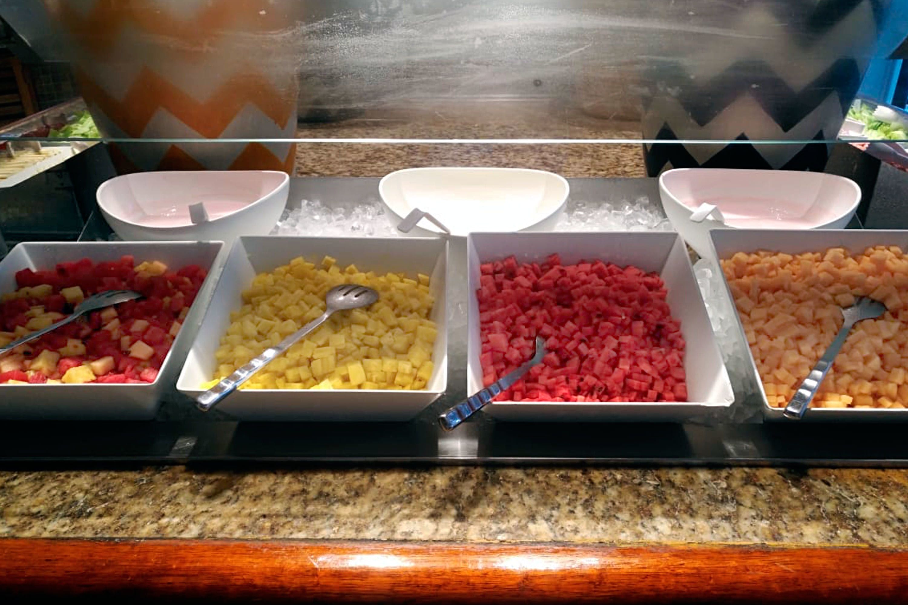 A buffet with various fruit options in bowls, arranged on a counter.