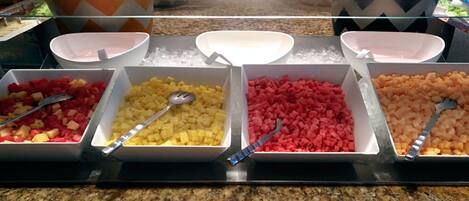 A buffet with various fruit options in bowls, arranged on a counter.