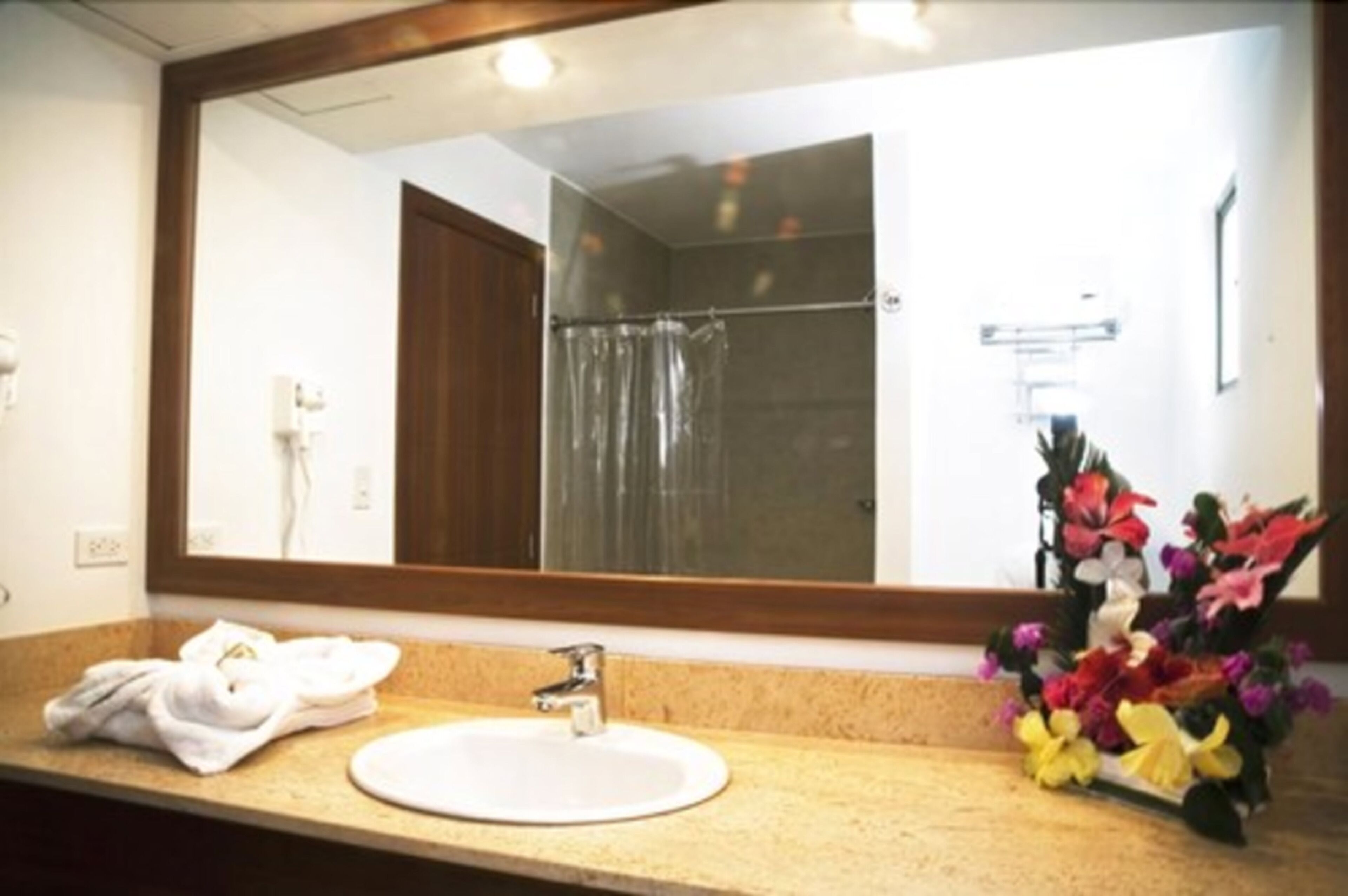 Un baño con lavamanos, espejo y ducha.