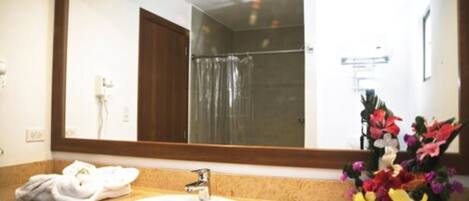 Un baño con lavamanos, espejo y ducha.