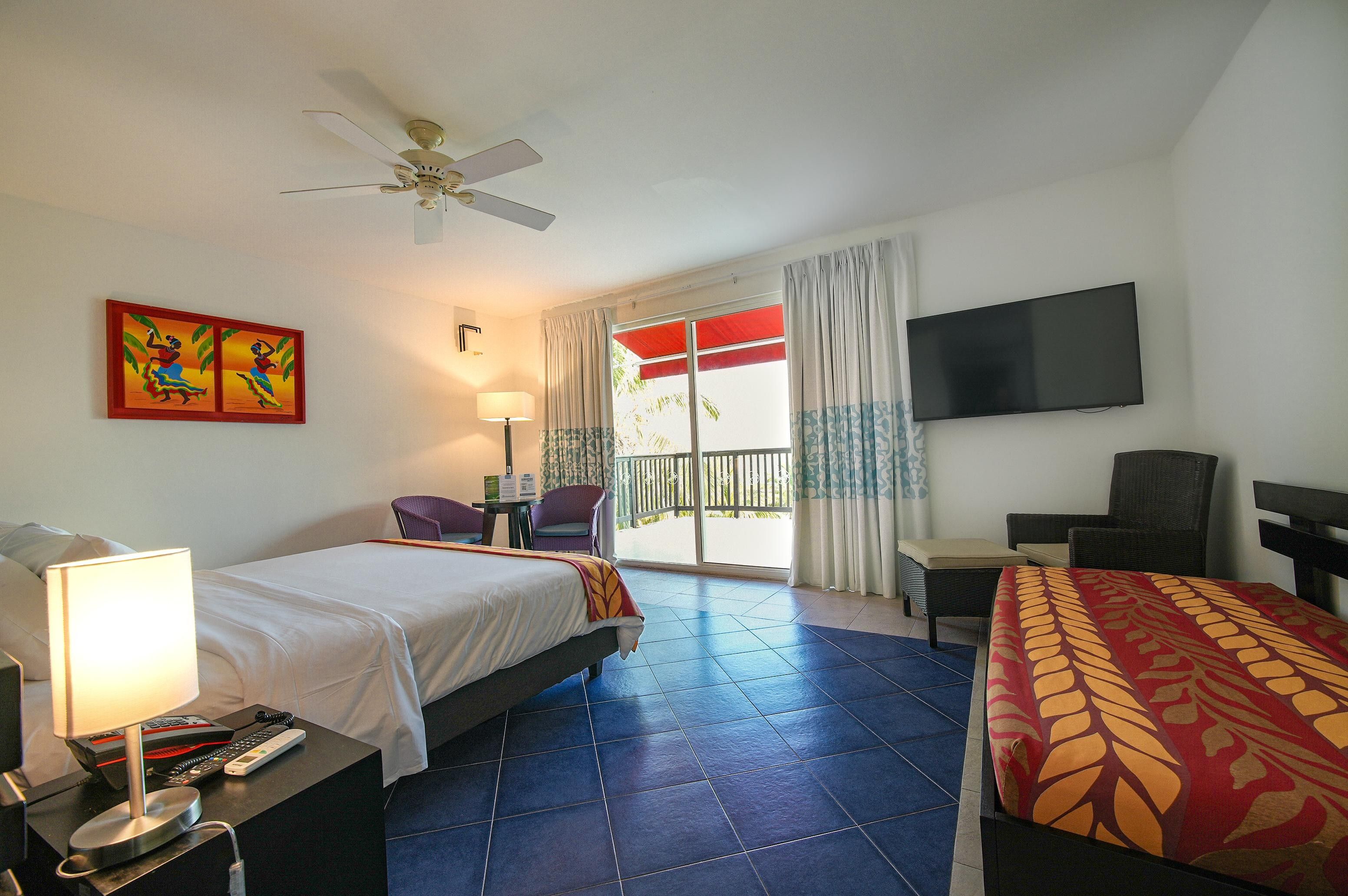 A hotel room with a bed, a desk, a chair, a television, a ceiling fan, and a window with curtains.