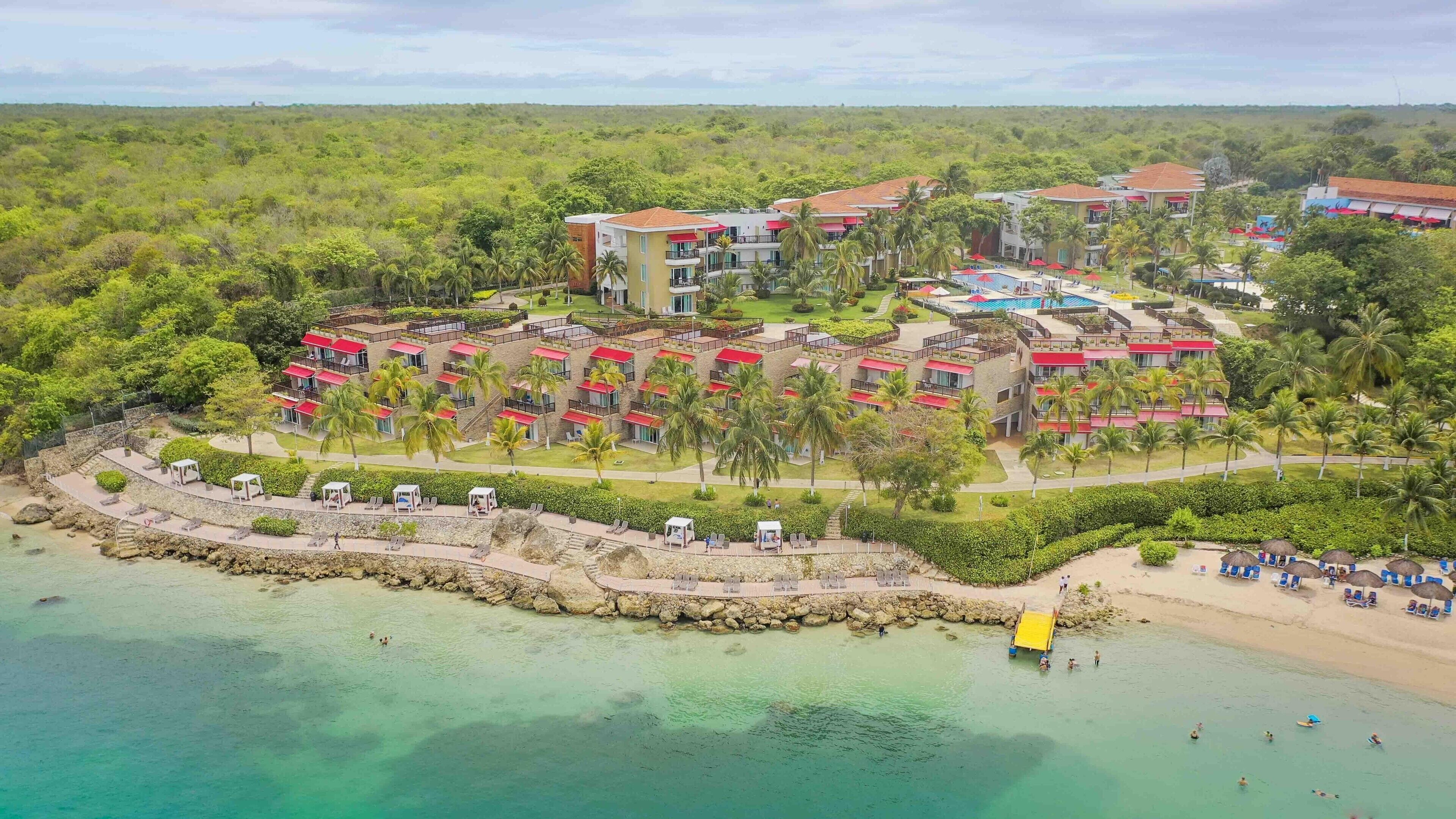 Um resort com vários edifícios, uma praia e águas turquesa cristalinas.