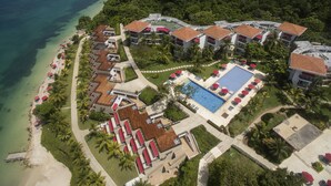 An aerial view of a resort with multiple buildings, a swimming pool, and a beach.