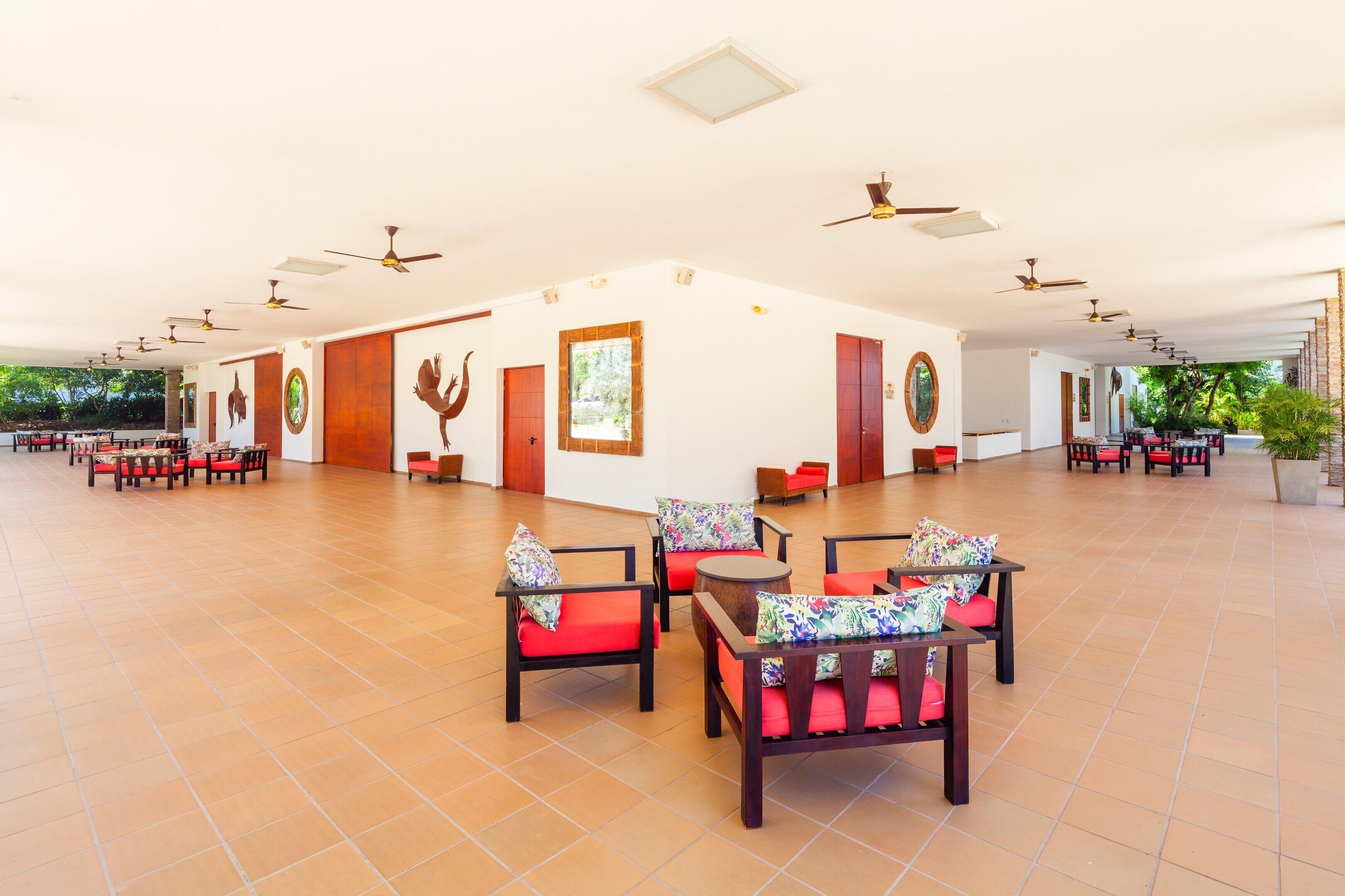 A spacious indoor area with multiple seating arrangements, ceiling fans, and a view of the outdoors.