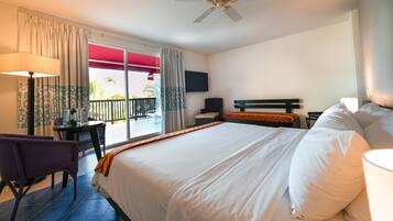 A hotel room with a bed, a desk, a chair, a TV, and a balcony with a view.
