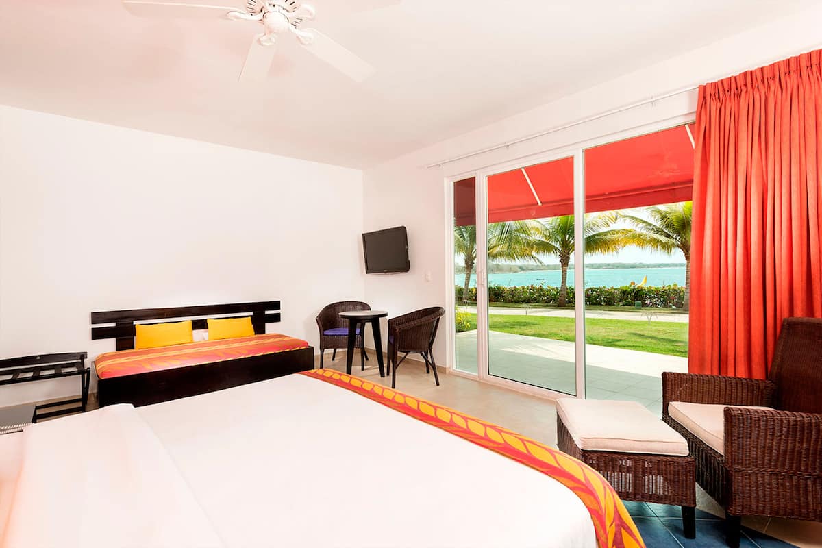 A hotel room with a bed, a desk, a chair, and a view of the ocean.