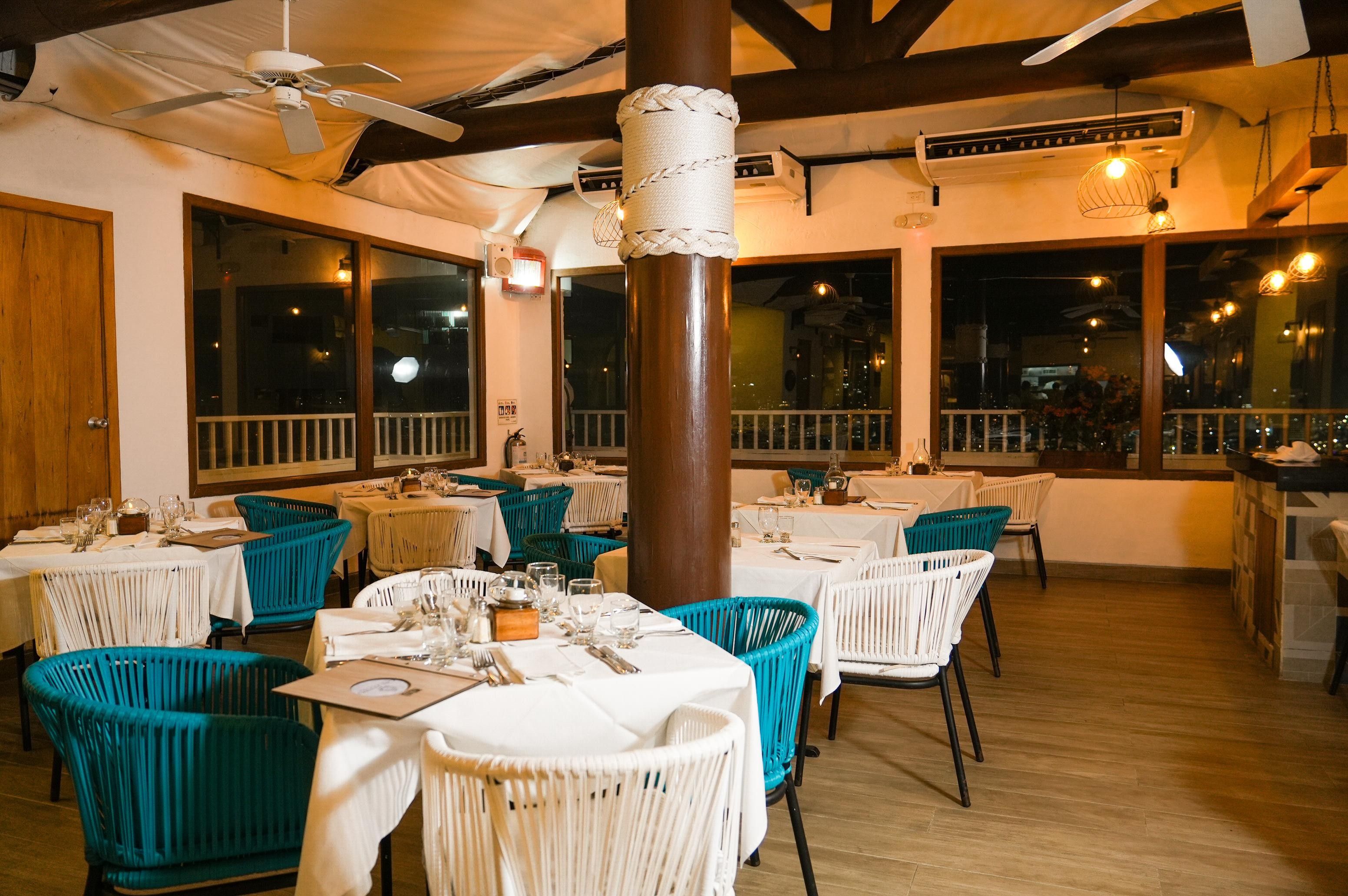 Un restaurante con mesas dispuestas para comer, sillas y un pilar grande.