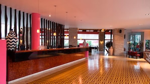 A hotel lobby with a reception desk, patterned floor, and modern decor. - Decameron Baru - All inclusive (Cartagena)