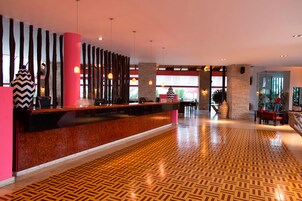 Un vestíbulo de hotel con mostrador de recepción, suelo estampado y decoración moderna.