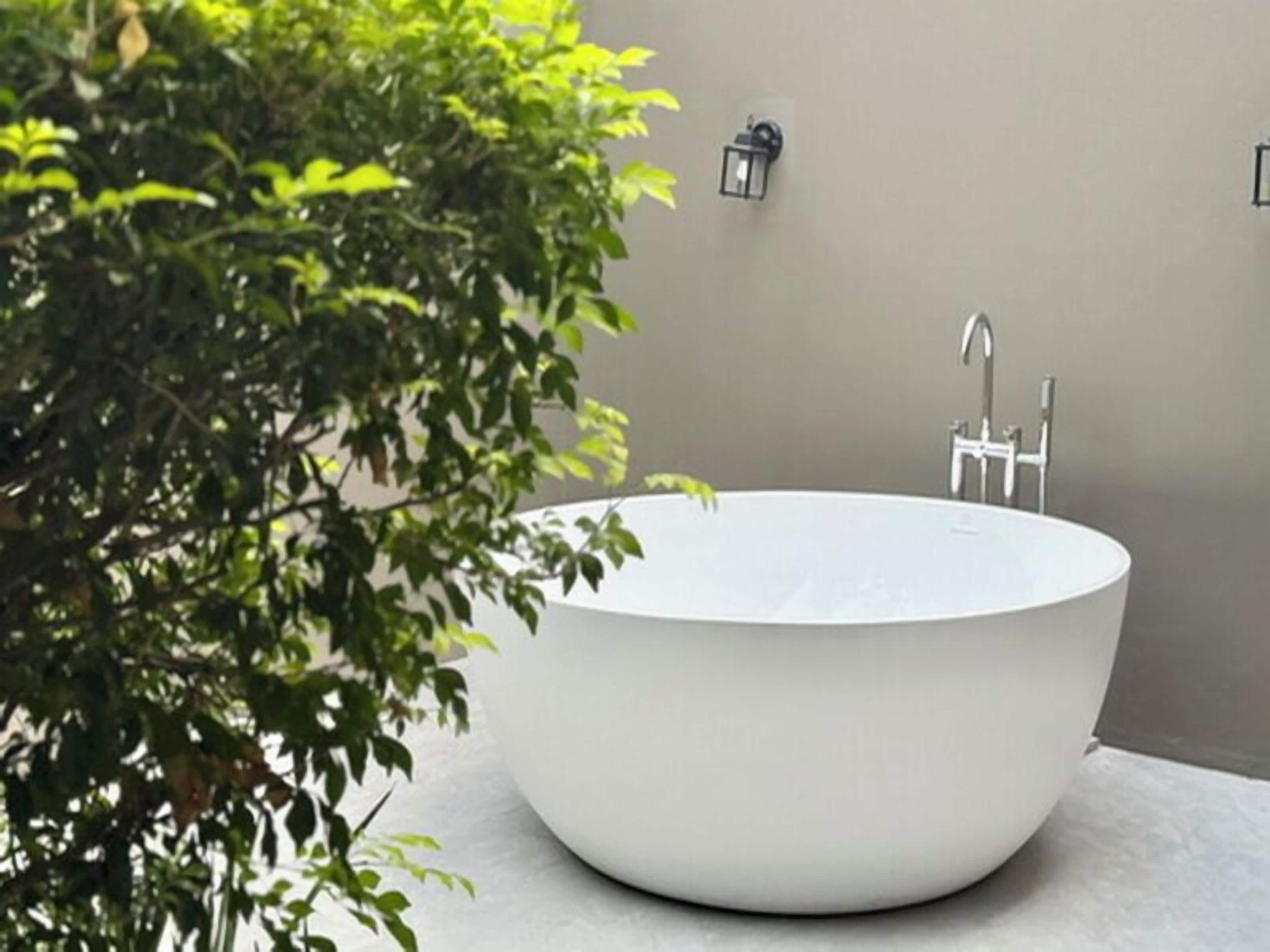 Un baño moderno con una bañera independiente, un aplique de pared y un grifo.