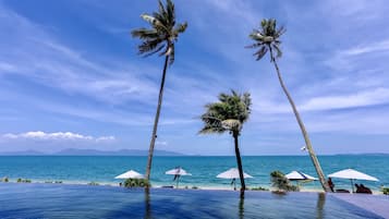 Una piscina al aire libre, sombrillas, sillones reclinables de piscina