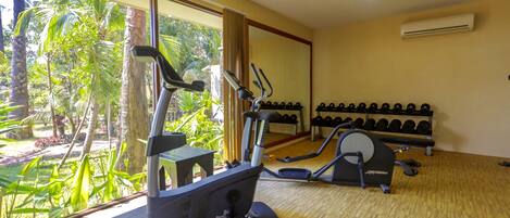 A gym with exercise equipment and a view of a tropical garden.
