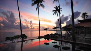 A serene poolside area with lounge chairs and umbrellas, overlooking a calm body of water at sunset. - Saree Samui Natures Finest Resort (Koh Samui)
