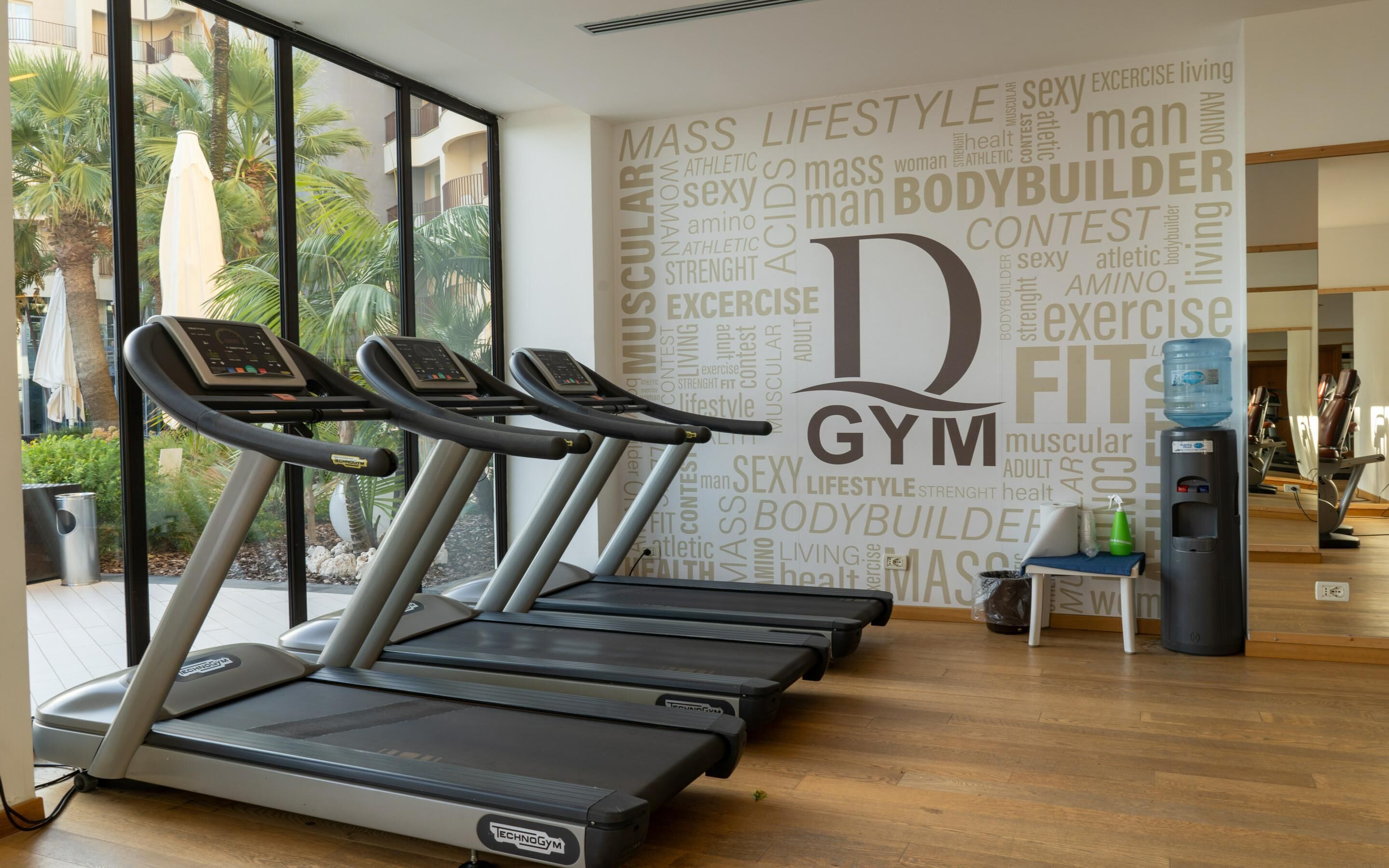 A gym with treadmills, a water dispenser, and a wall with motivational words.
