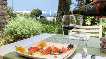 A table set with a plate of food, a wine glass, and a bottle of wine being poured.