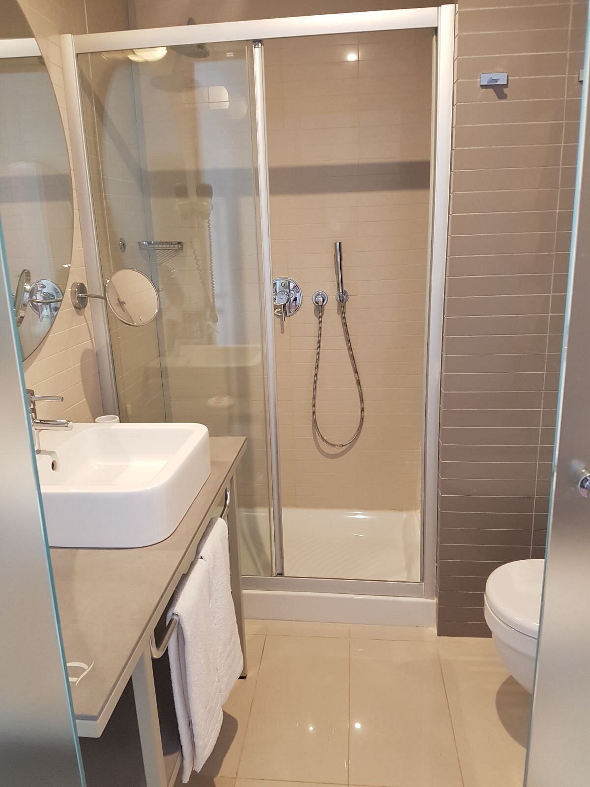 A modern bathroom with a glass-enclosed shower, a white sink, and a toilet.
