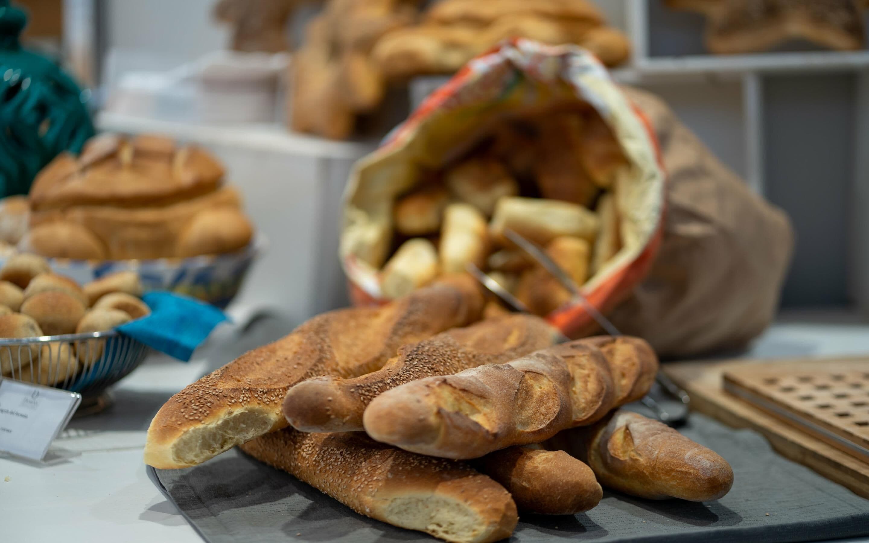 Une variété de pains et de viennoiseries étaient exposés, notamment un sachet de gressins et un panier de petits pains ronds.