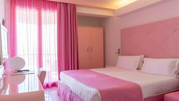 Habitació d'hotel amb un llit, una taula de treball, una cadira i un armari.