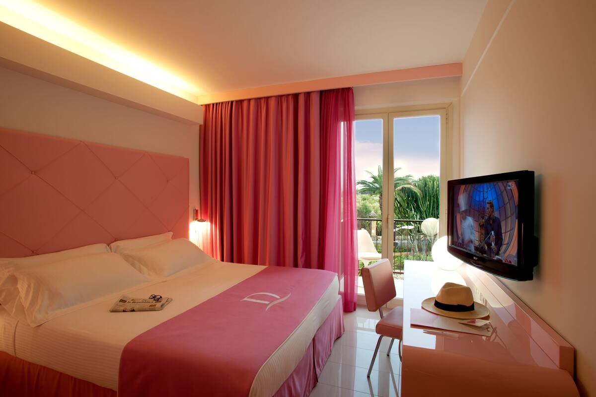 A hotel room with a bed, a television, a chair, and a window with curtains.