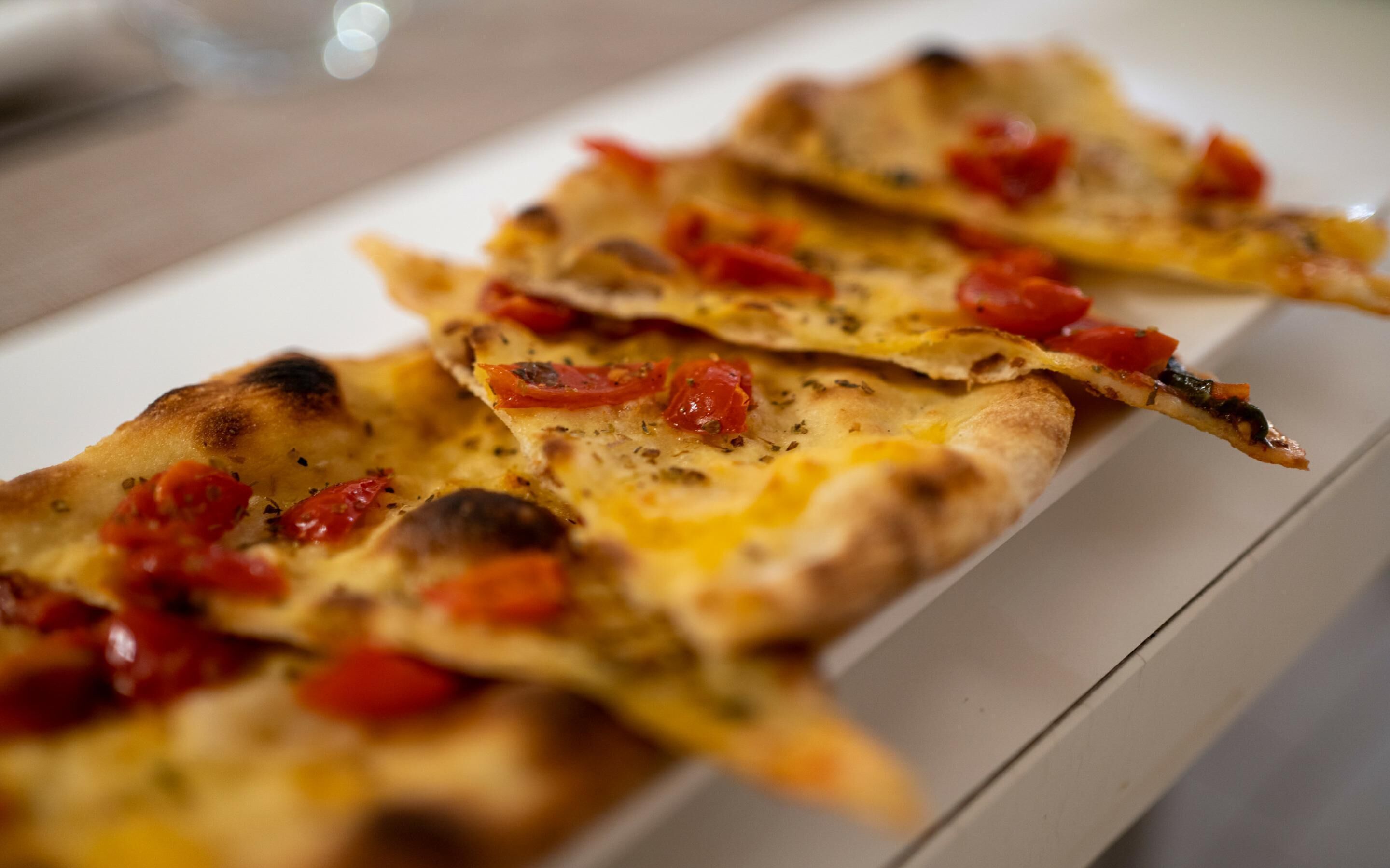 A tray of flatbread pizzas with tomatoes and herbs.