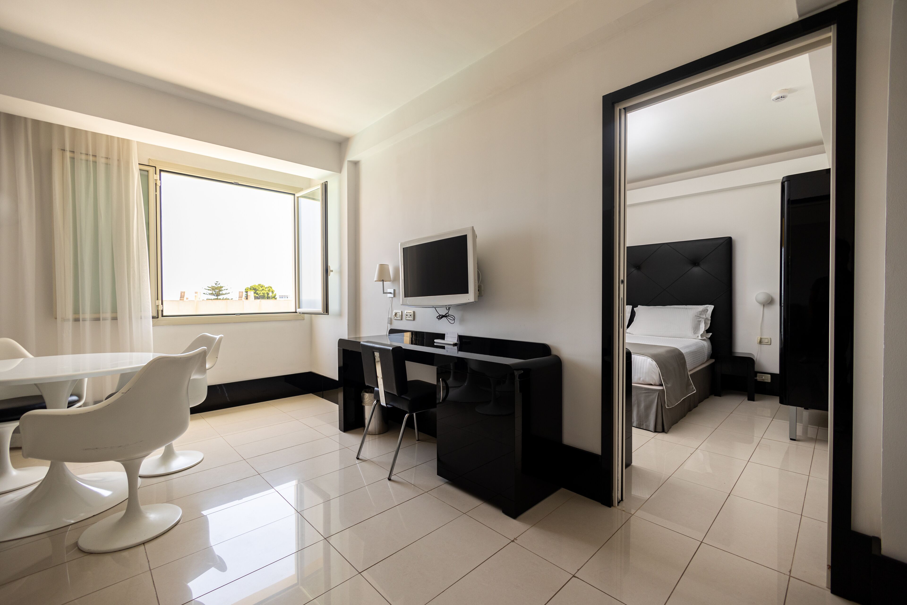A modern hotel room with a desk, chair, and bed.